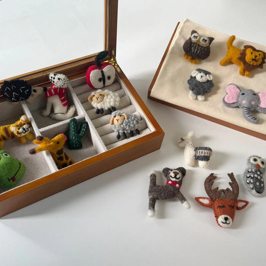 Handmade wool felt animal and botanical brooch collection displayed in jewelry trays