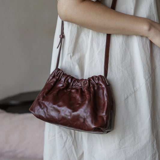 Dark brown ruched leather cloud bag worn crossbody