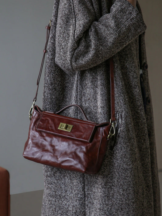 Chestnut brown leather satchel worn with its adjustable shoulder strap
