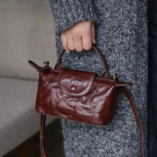 Coffee brown vegetable-tanned leather mini crossbody bag carried by the top handle