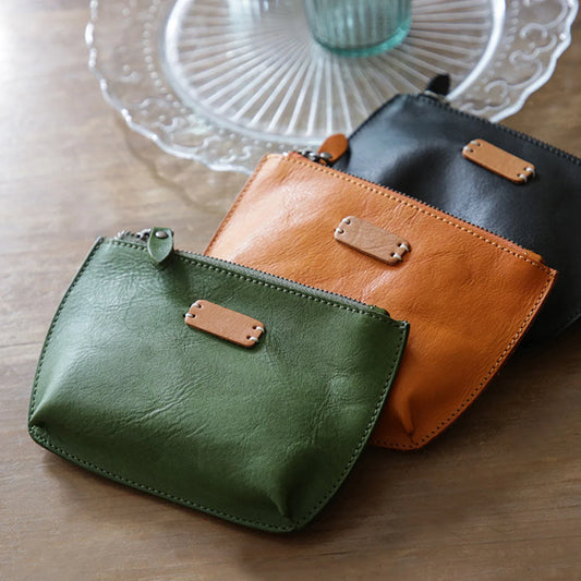 Black, sunset yellow, and matcha green leather cosmetic pouches arranged on a table