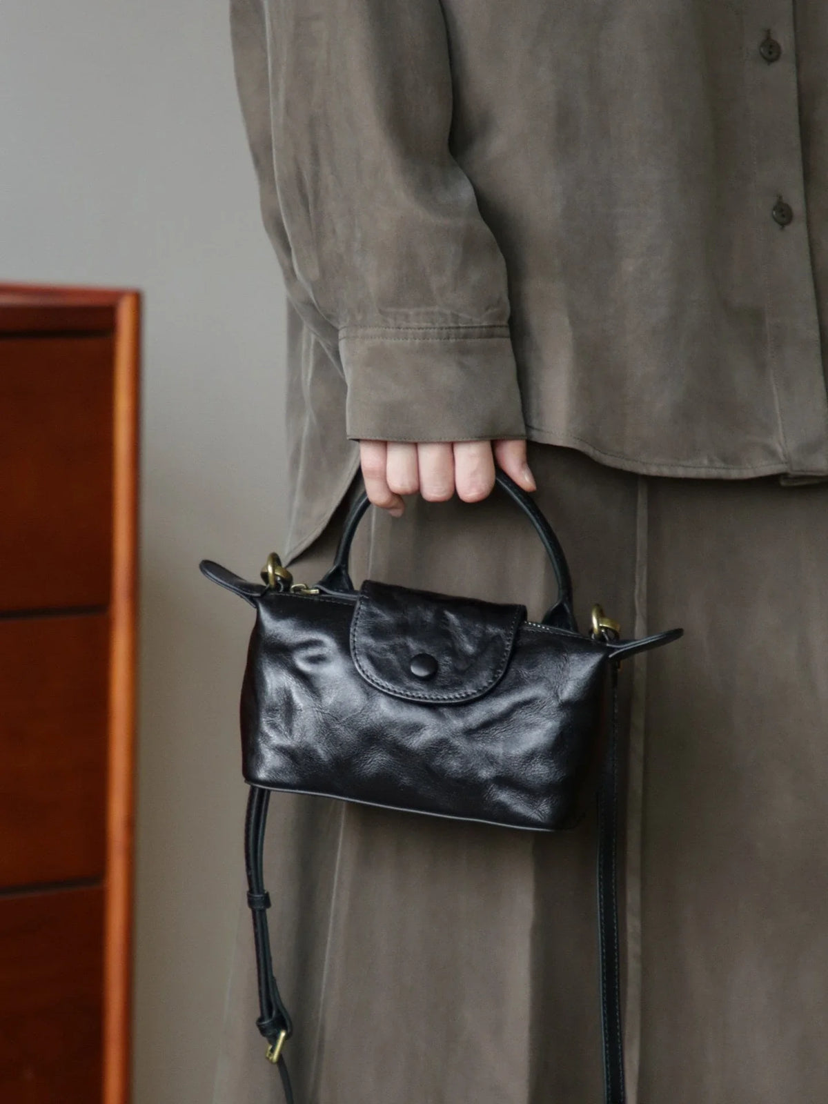 Black vegetable-tanned leather mini bag carried by the top handle