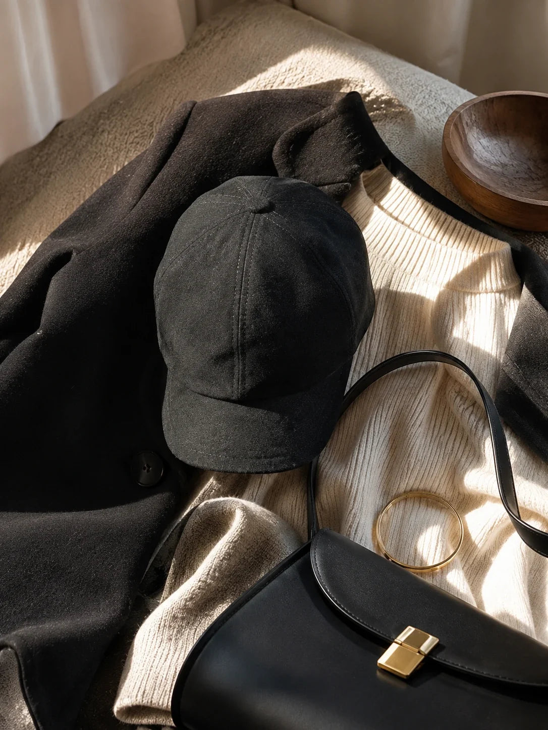 Black suede lambskin beret cap styled with a black coat, cream knitwear and a black bag