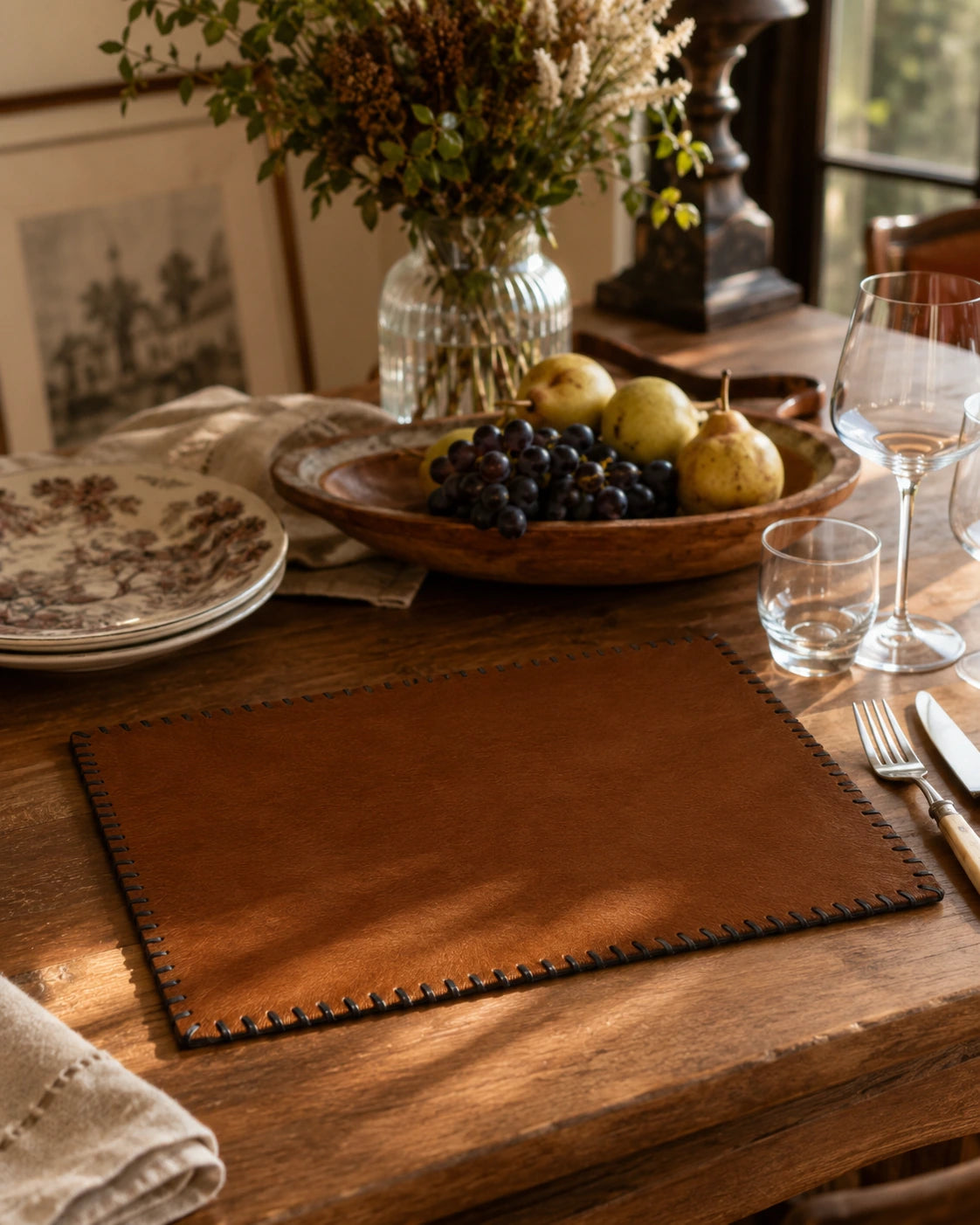 Solid brown genuine cowhide placemat styled on a warm wood dining table
