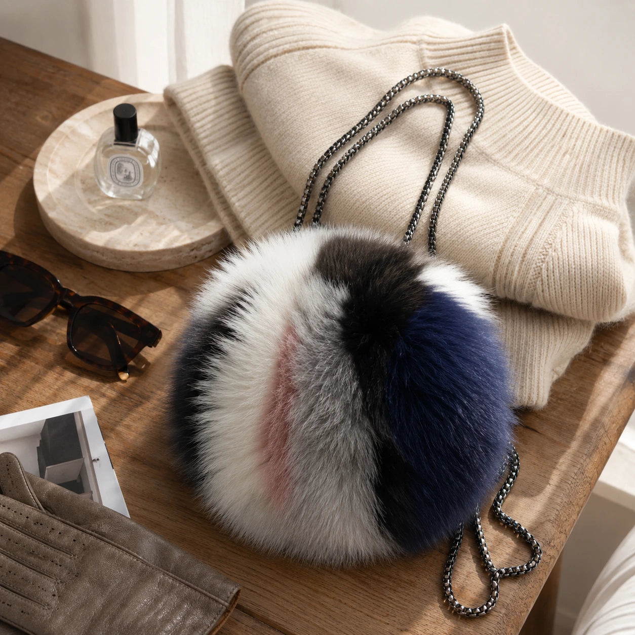 Capricornus Living Random colorblock genuine fox fur round bag styled with neutral knitwear and accessories