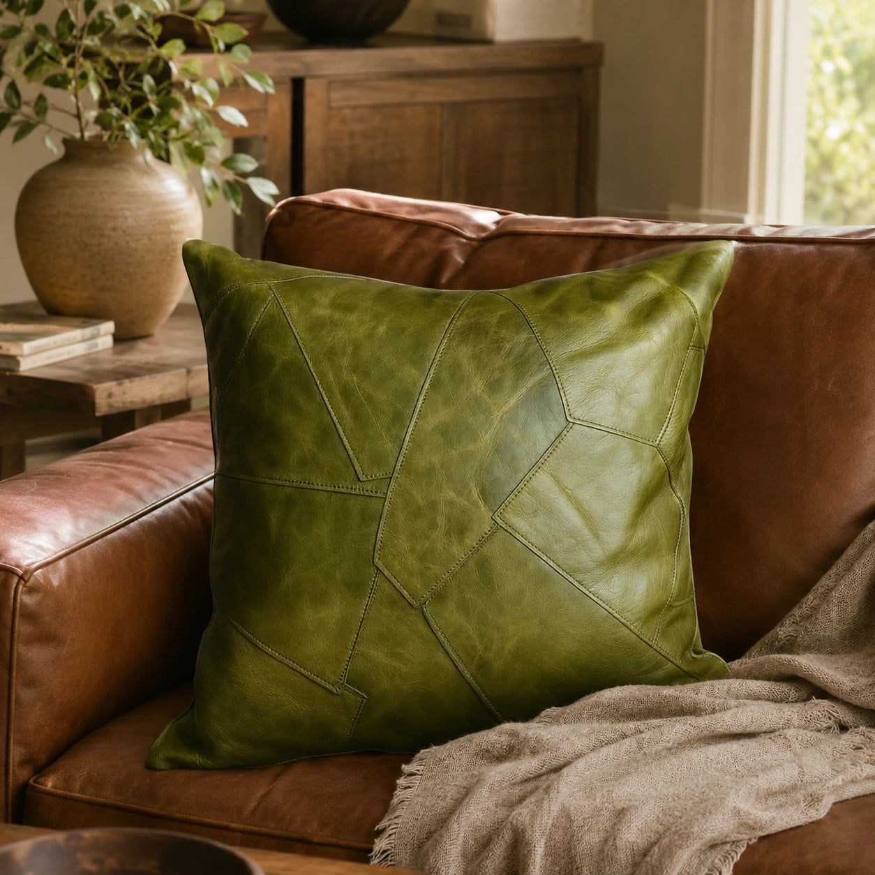 Capricornus Living Tundra Olive Green square genuine cowhide patchwork pillow styled on a leather chair