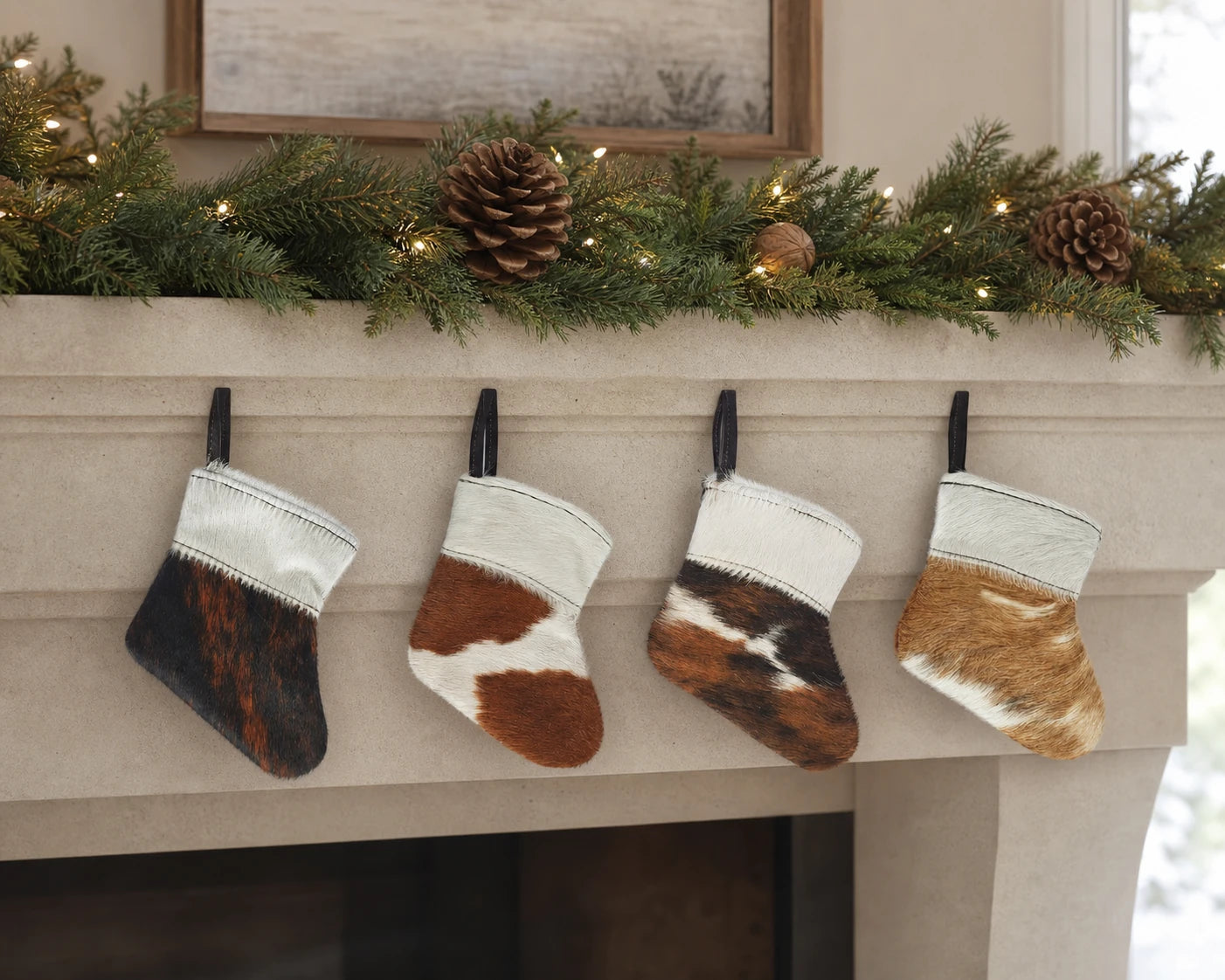 Capricornus Living Four-piece cowhide mini holiday stocking ornament set on a contemporary limestone mantel