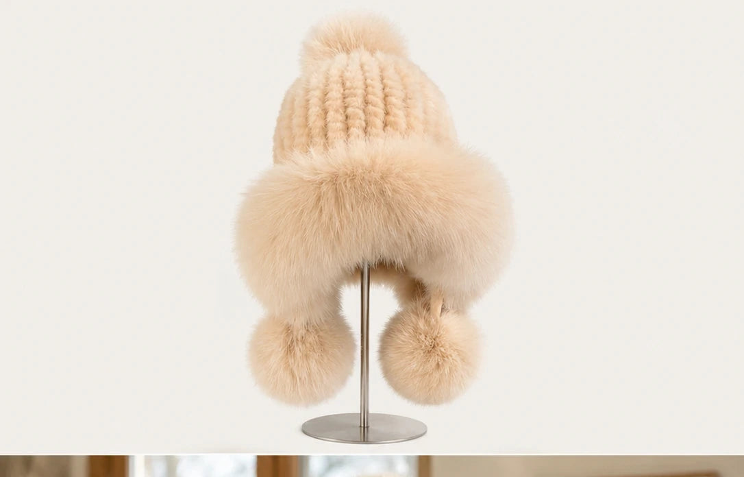 Soft ivory genuine mink and fox fur earflap hat displayed on a minimal metal stand