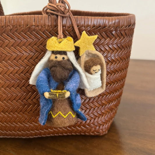 Handmade wool felt King and Little Prince bag charms on a woven leather tote