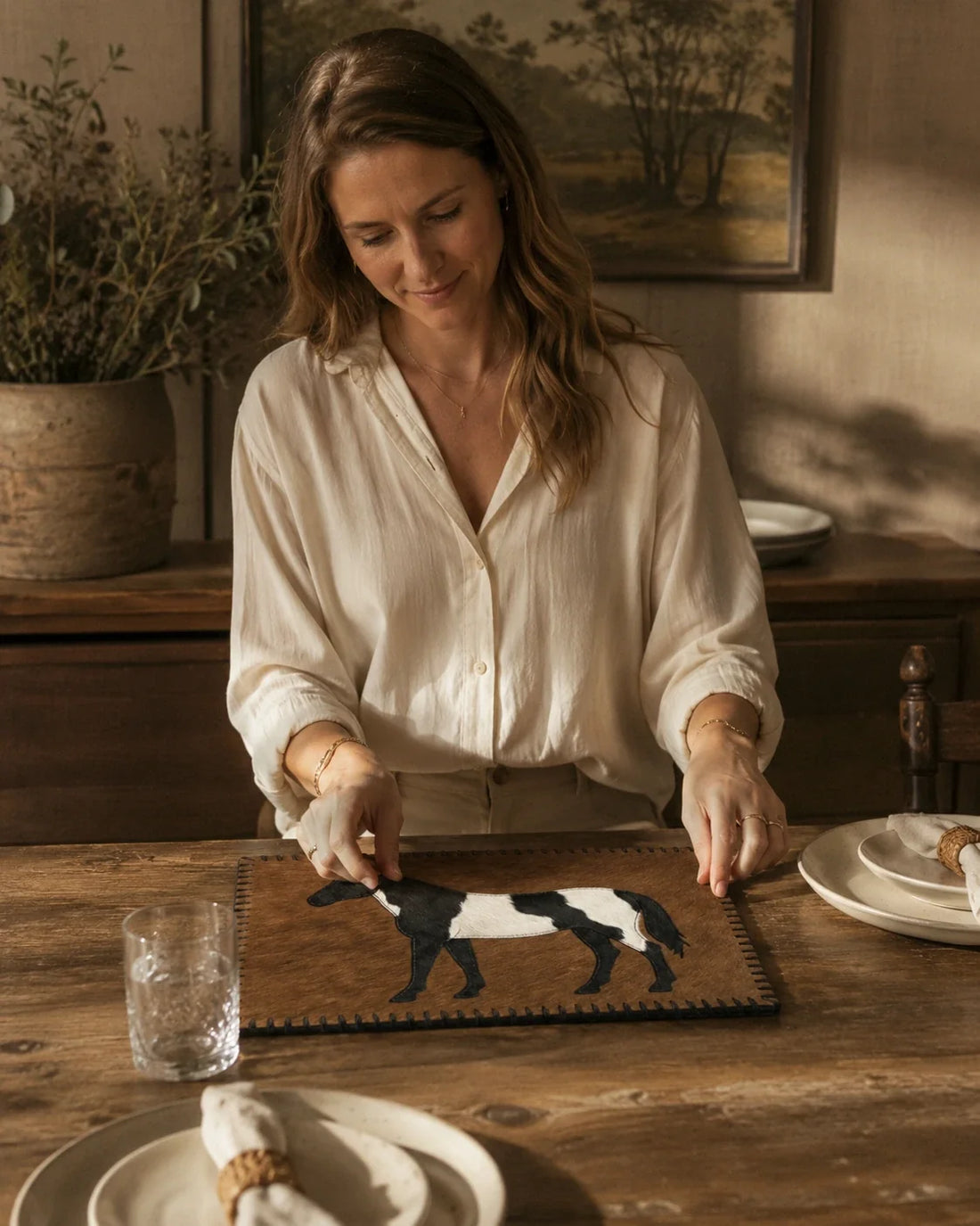 Woman setting a dining table with a brown horse-inlay genuine cowhide placemat