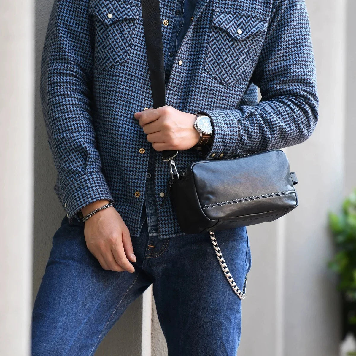 Men's black top-grain cowhide crossbody bag worn with a detachable strap