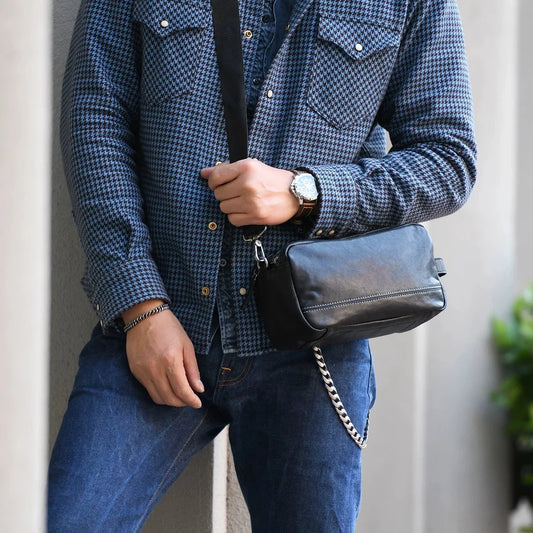 Men's black top-grain cowhide crossbody bag worn with a detachable strap