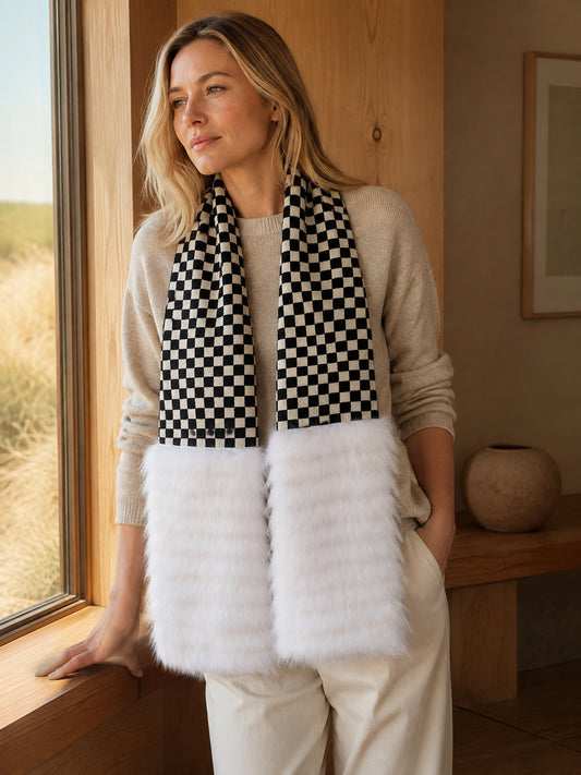 Woman wearing a black-and-white checkerboard fox fur scarf in a warm winter interior