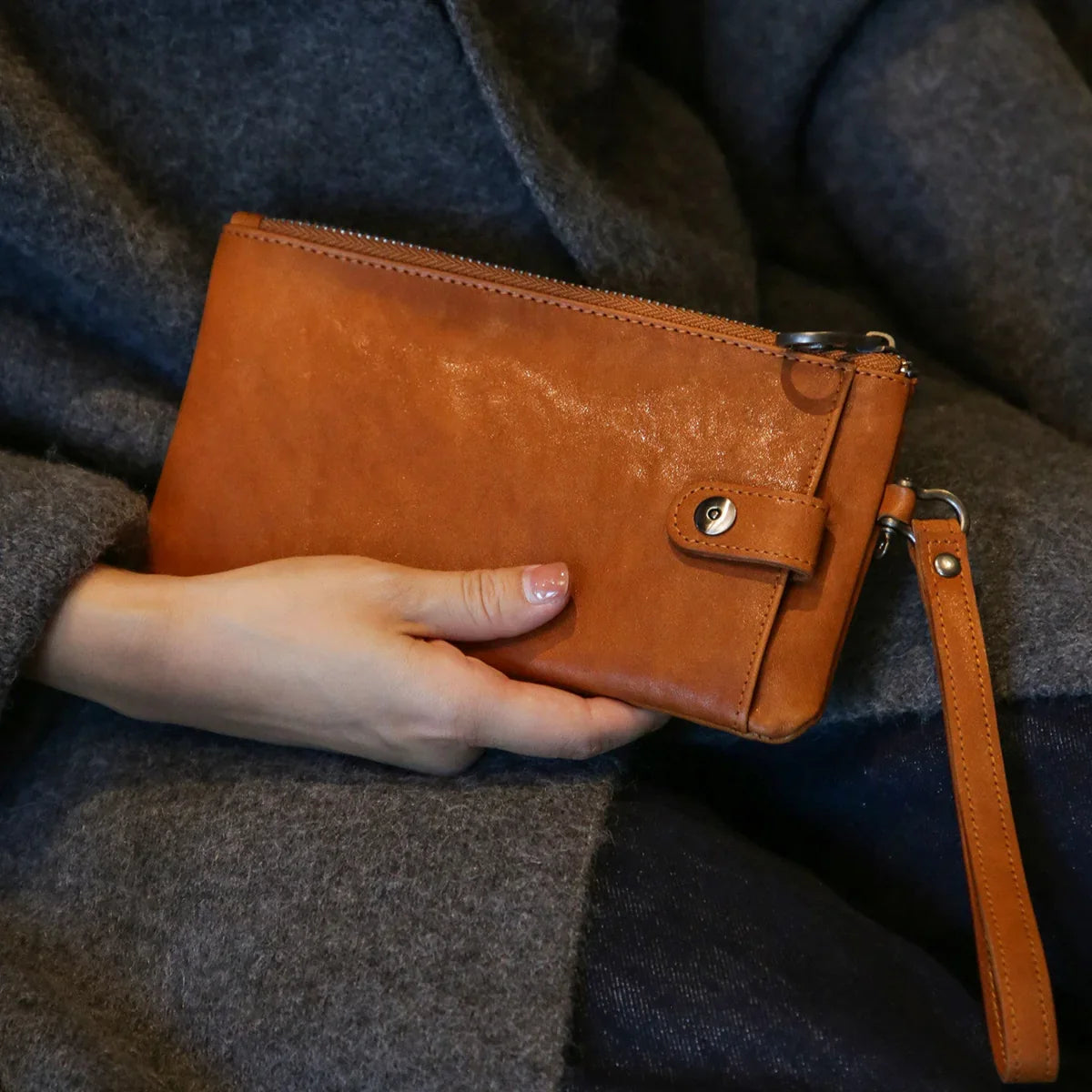 Brown vegetable-tanned leather long wallet carried as a wristlet