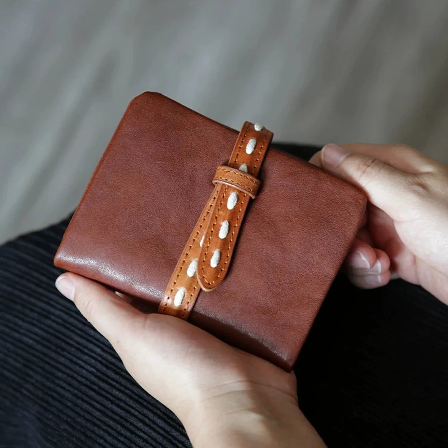Brown vegetable-tanned leather bifold wallet with contrast strap closure