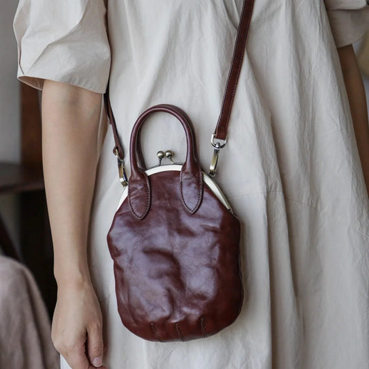 Brown vegetable-tanned leather kiss-lock crossbody phone bag worn at the side