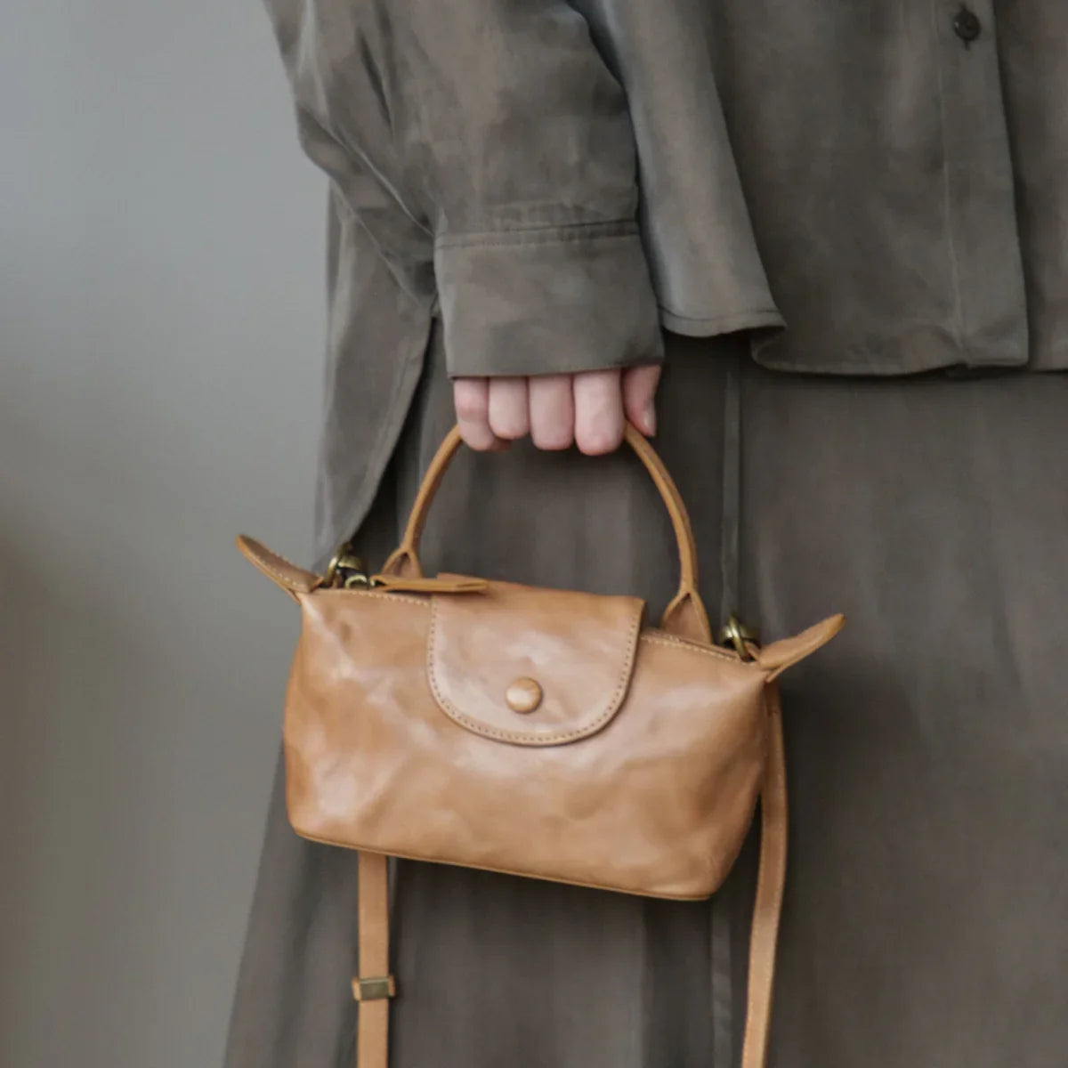 Chestnut brown vegetable-tanned leather mini crossbody bag carried by the top handle