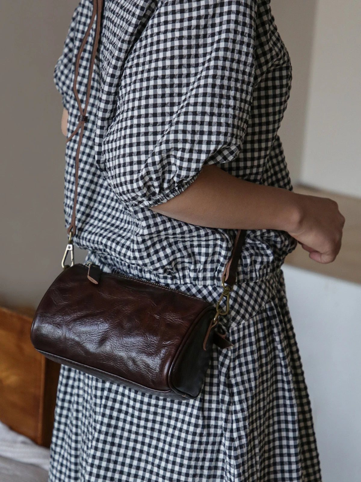 Coffee brown vegetable-tanned leather barrel crossbody bag worn over the shoulder