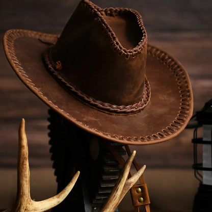 Men's hand-stitched cowhide western cowboy hat in a warm rustic setting