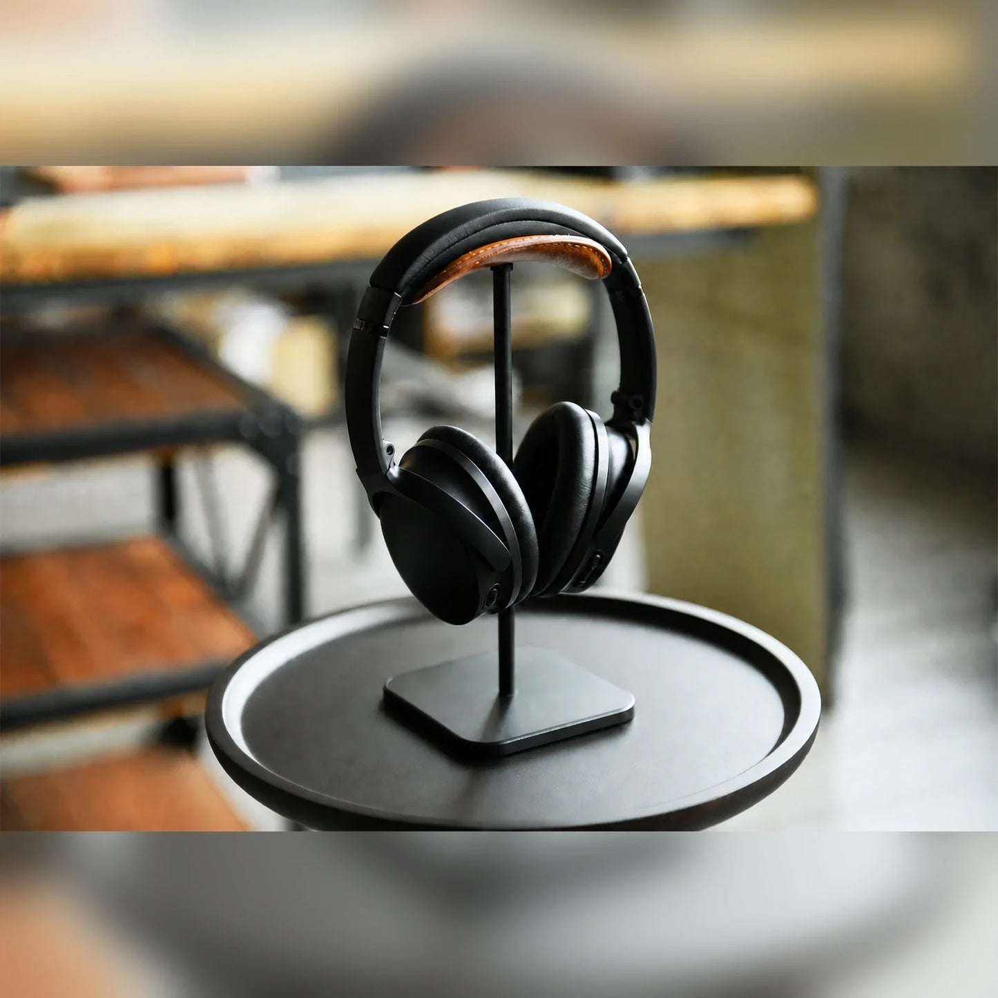 Hand-stitched tan cowhide headphone stand with headphones in a warm desk setting