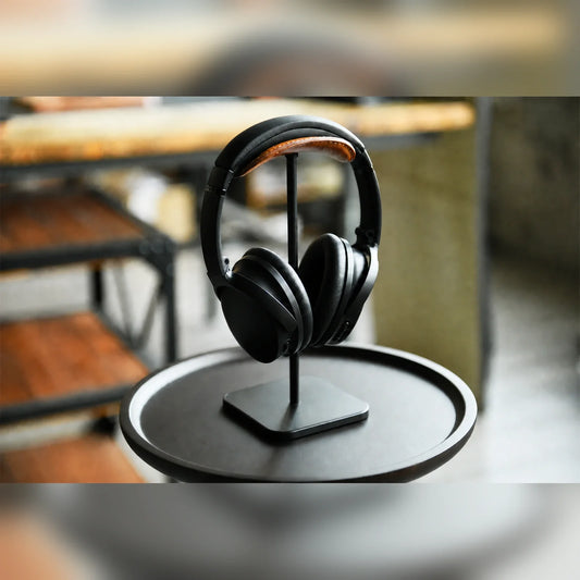 Hand-stitched tan cowhide headphone stand with headphones in a warm desk setting