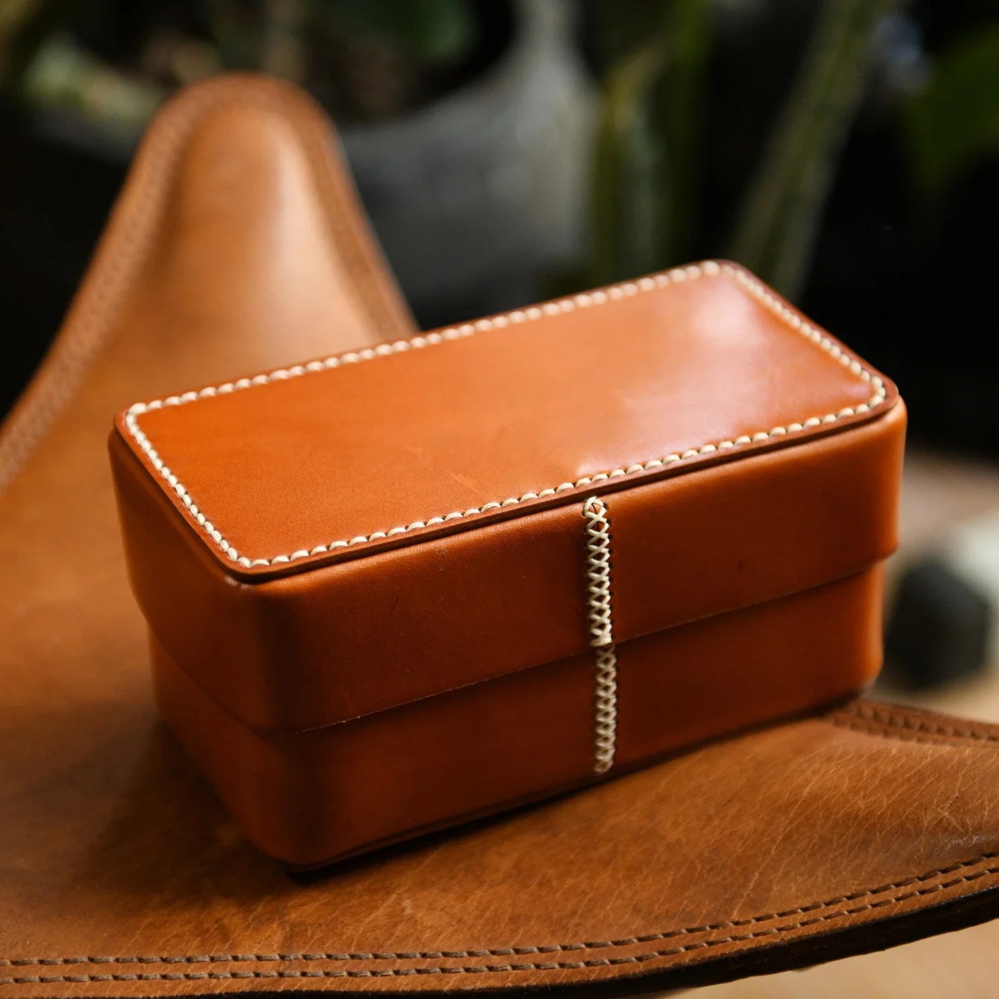 Hand-stitched brown leather keepsake box in a warm interior setting