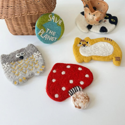 Handmade wool felt animal and mushroom coasters arranged with cups