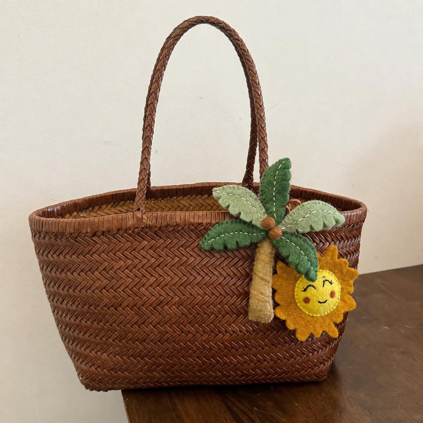 Handmade wool felt palm tree and smiling sun bag charm on woven basket