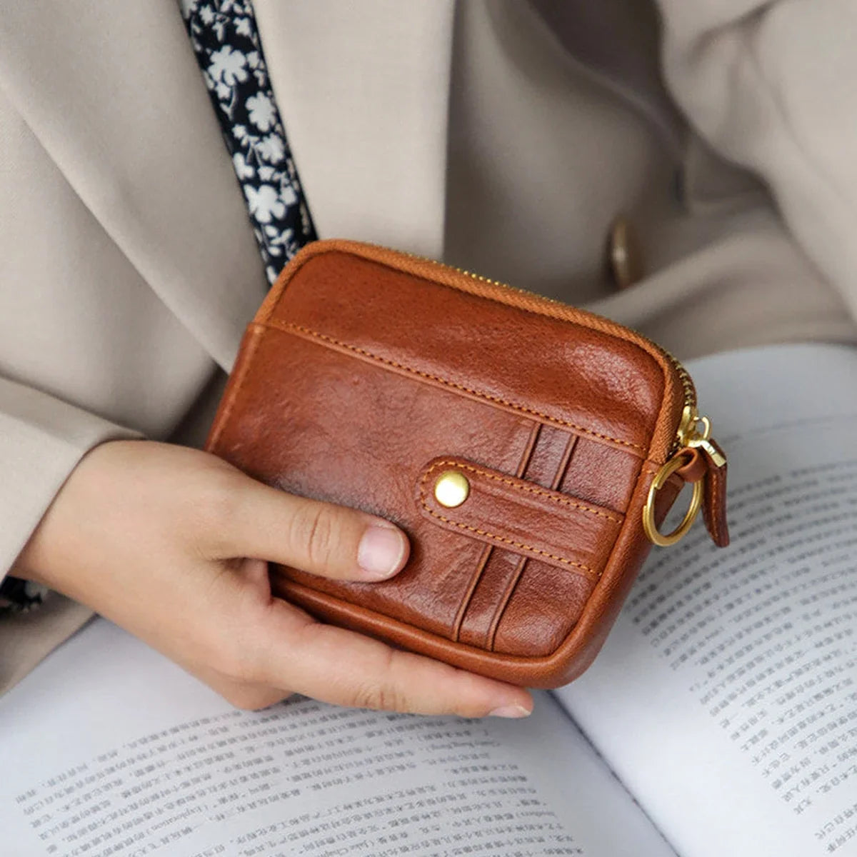 Vegetable-tanned leather coin purse held in an everyday reading setting