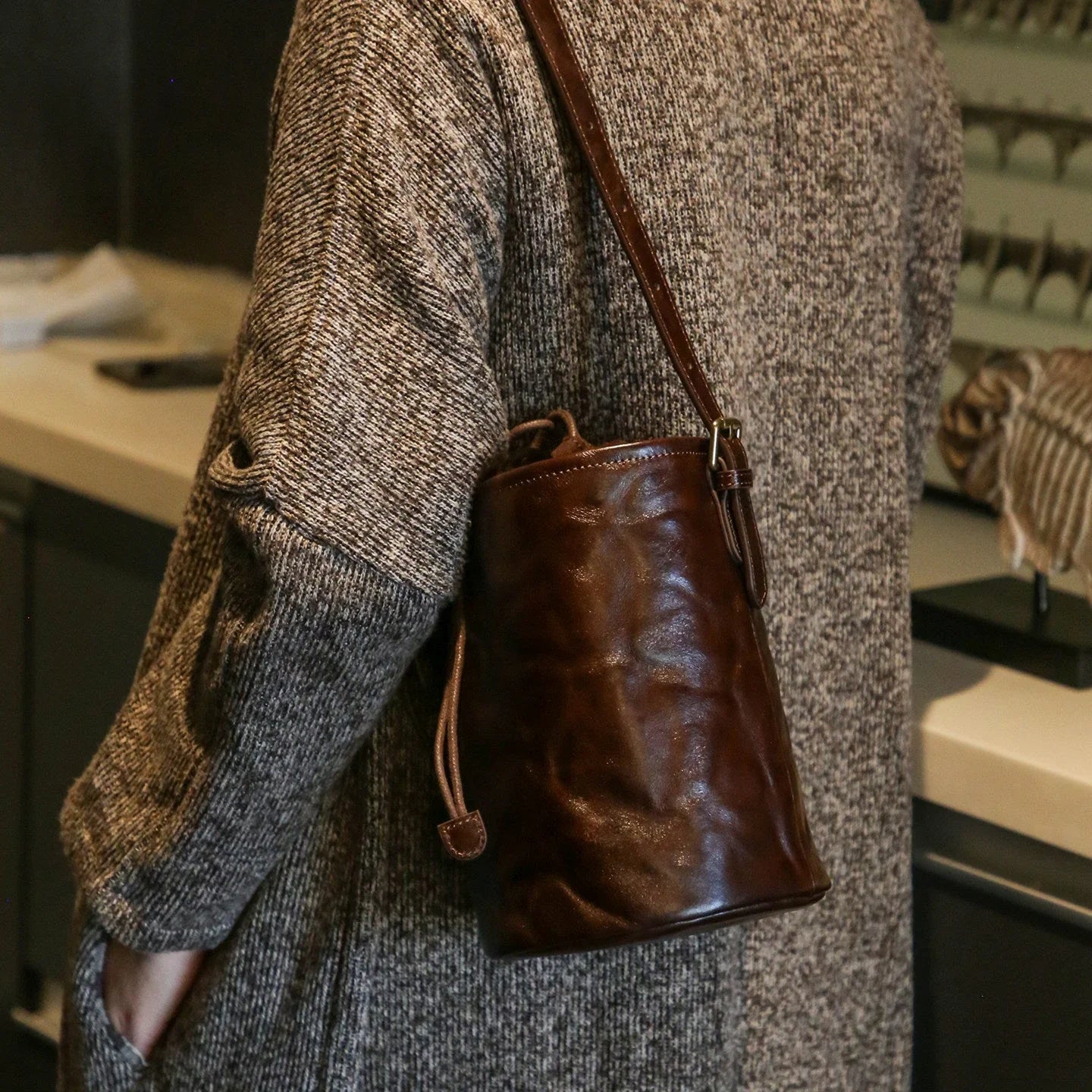 Ebony brown top-grain leather bucket bag worn over the shoulder