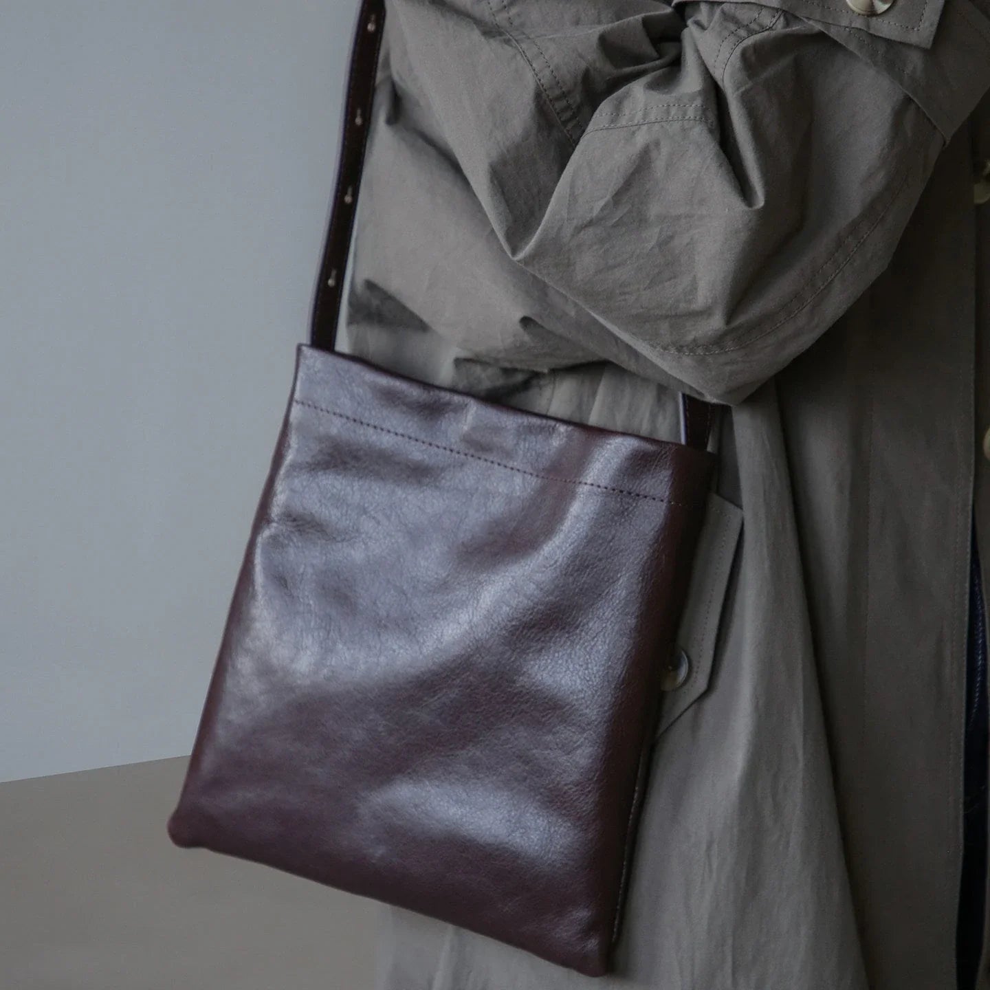 Ebony brown top-grain leather shoulder bag styled with a taupe coat