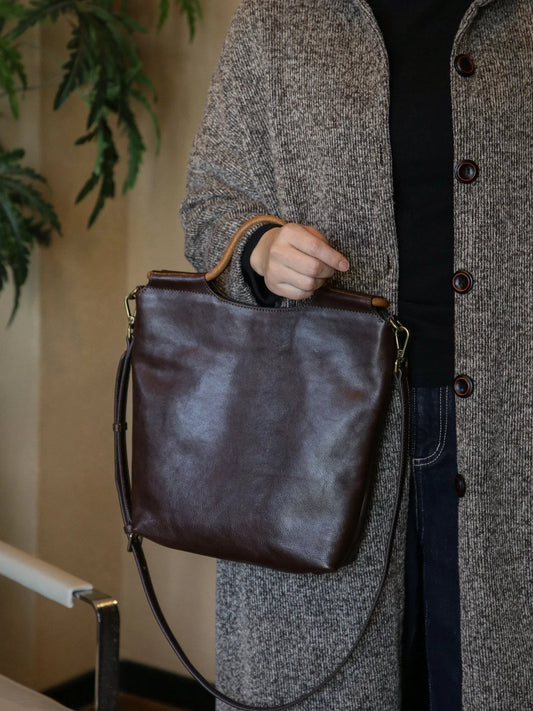 Ebony brown vegetable-tanned leather convertible tote bag carried by hand