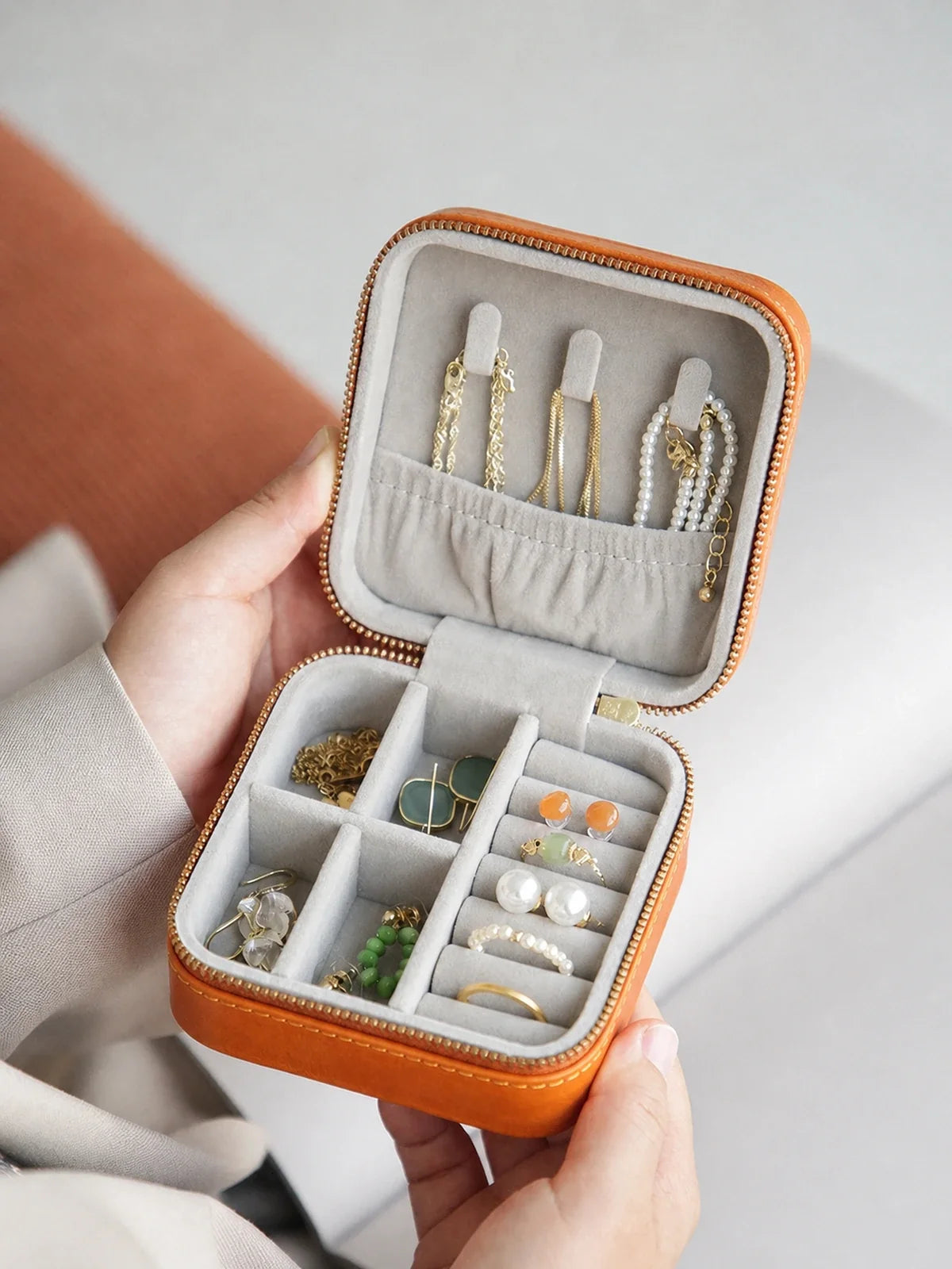 Open vegetable-tanned leather travel jewelry case with organized rings, earrings, and necklaces