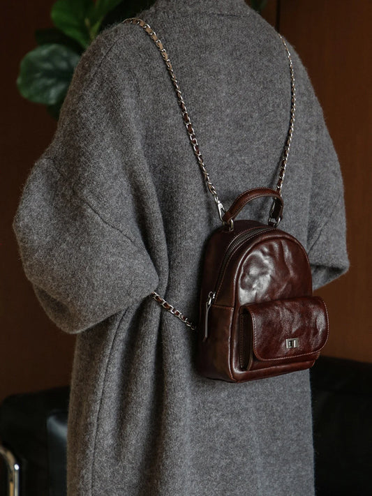 Ebony brown vegetable-tanned leather mini backpack worn over a grey coat