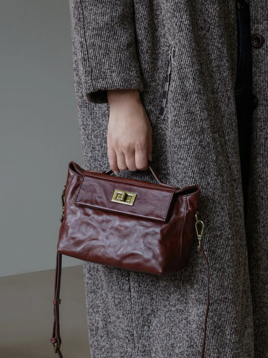 Chestnut brown vegetable-tanned leather satchel carried by the top handle
