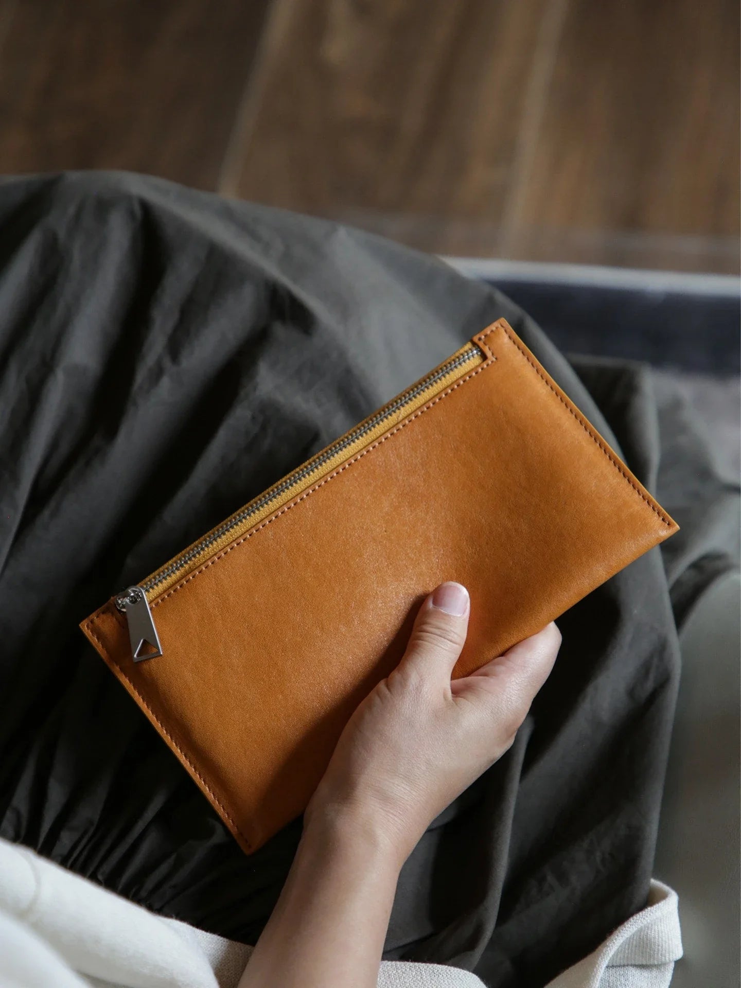 Caramel vegetable-tanned top-grain leather slim long wallet held by hand