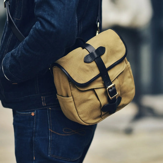 Waxed canvas and vegetable-tanned leather messenger bag worn crossbody in brown