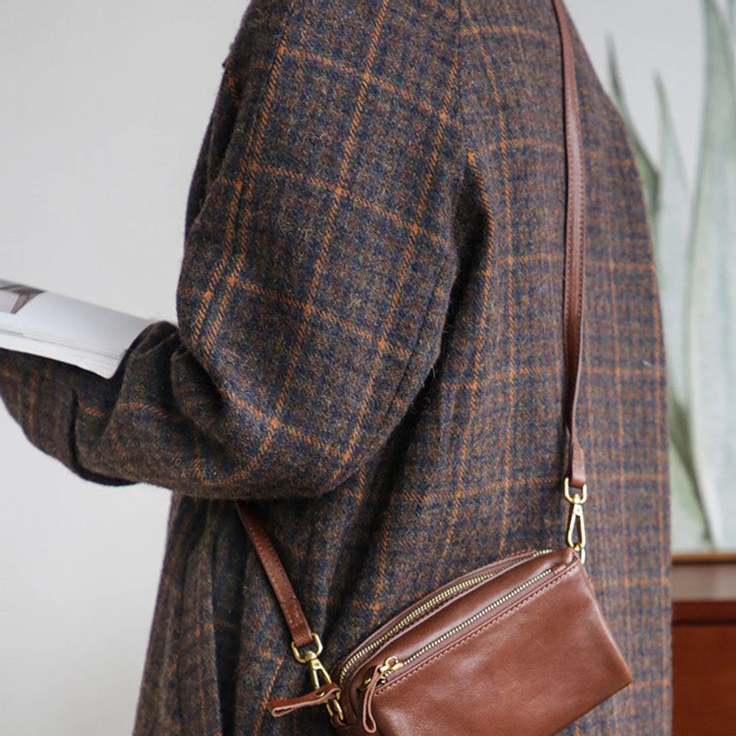 Women's brown top-grain leather crossbody bag styled with a plaid coat