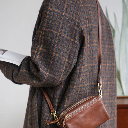 Women's brown top-grain leather crossbody bag styled with a plaid coat