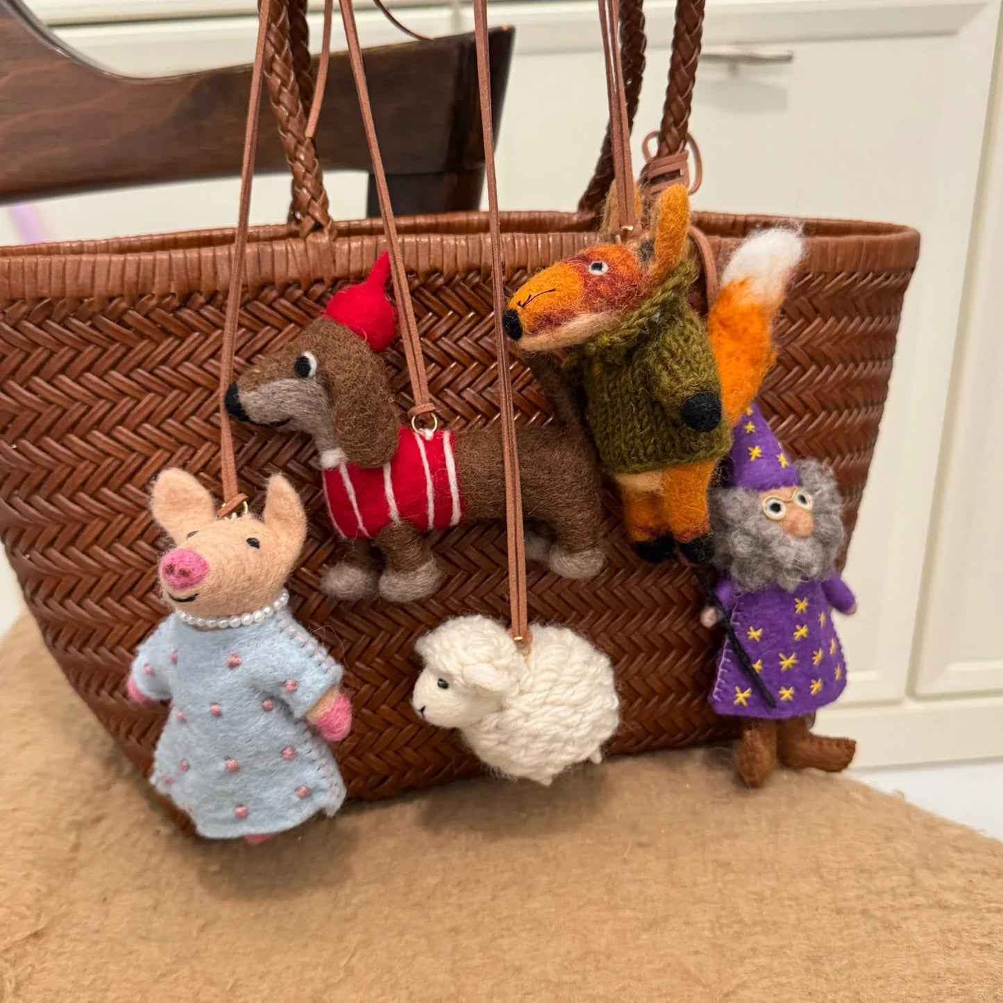 Handmade wool felt animal bag charms collection on a woven bag