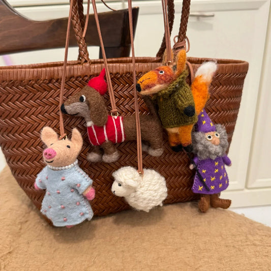 Handmade wool felt animal bag charms collection on a woven bag