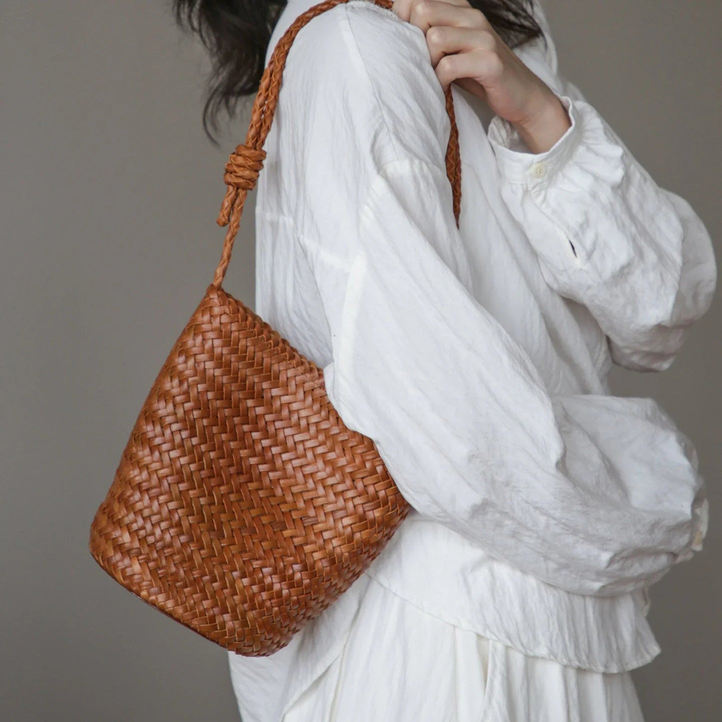Brown woven vegetable-tanned top-grain leather bucket bag worn on the shoulder