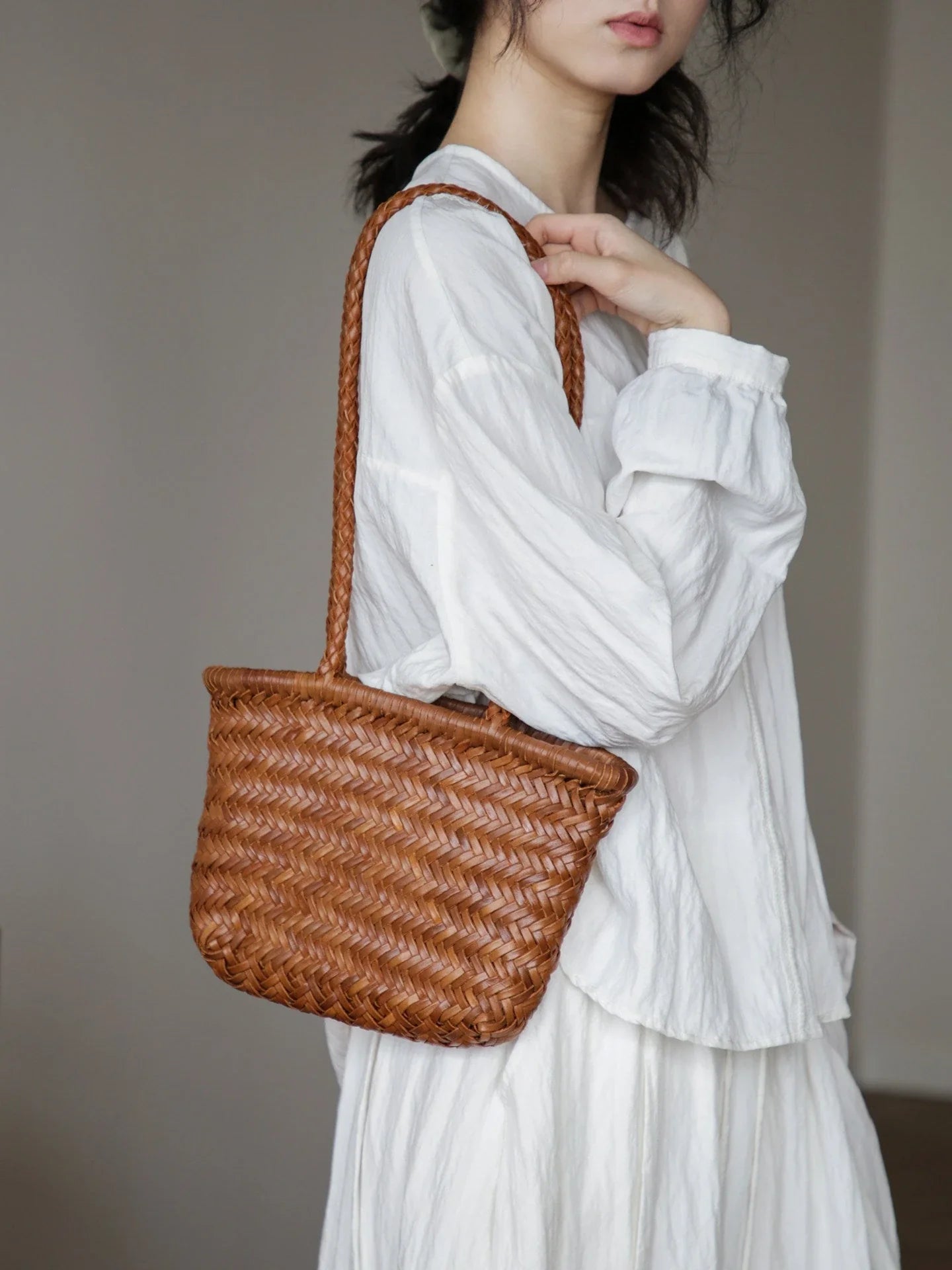Vegetable-tanned woven leather shoulder bag in brown, styled with white clothing