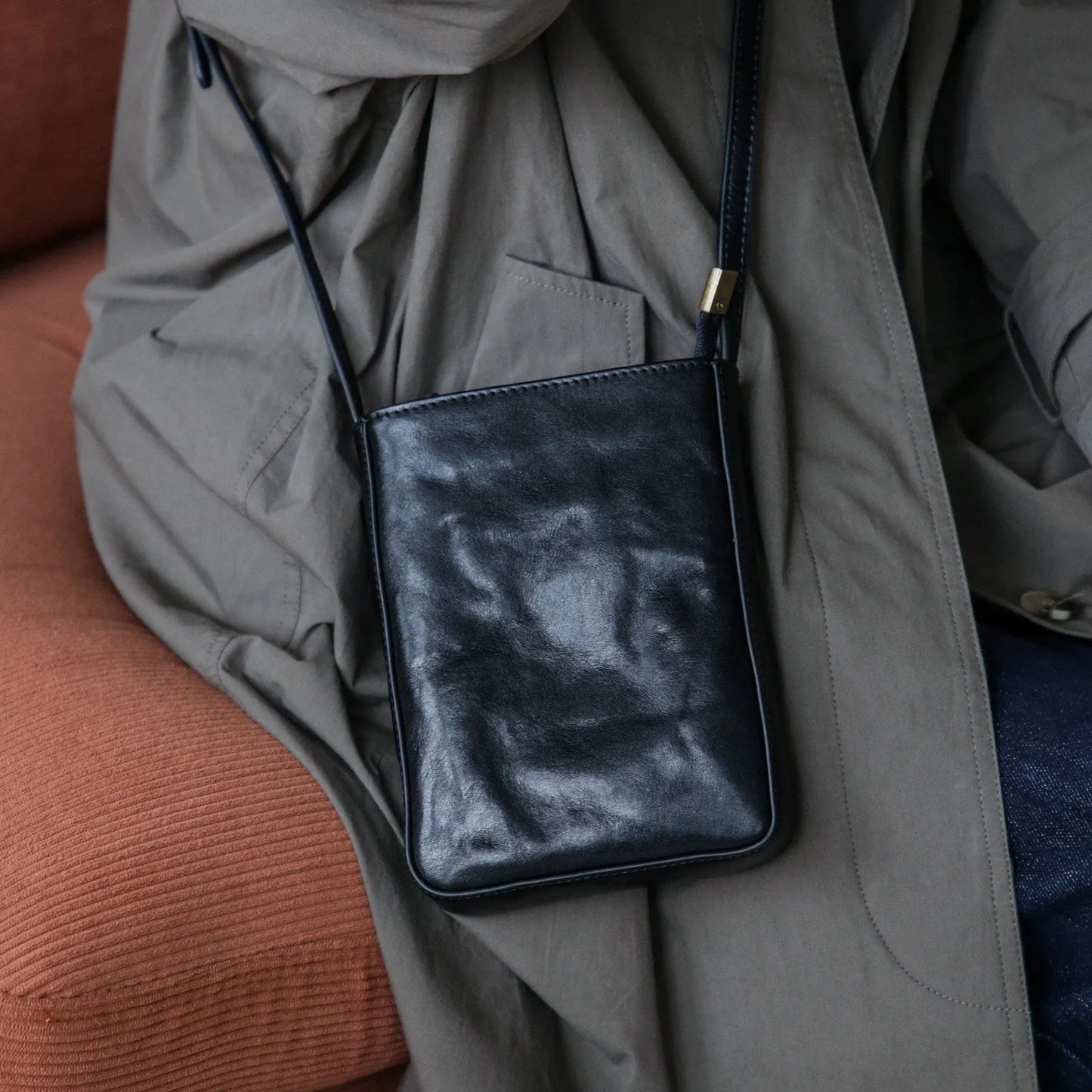 Black top-grain leather phone crossbody bag, seated worn view