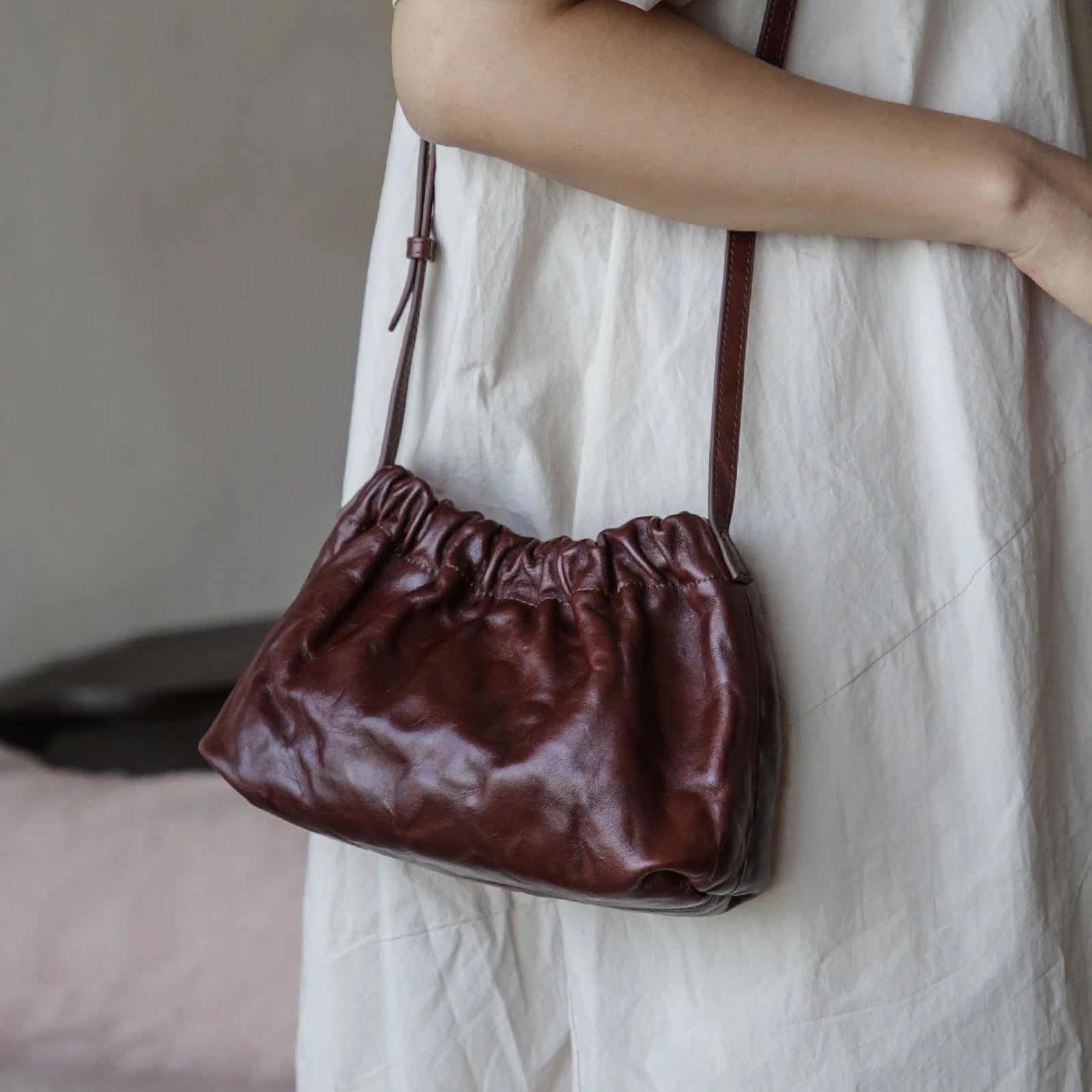 Dark brown ruched leather cloud bag worn crossbody