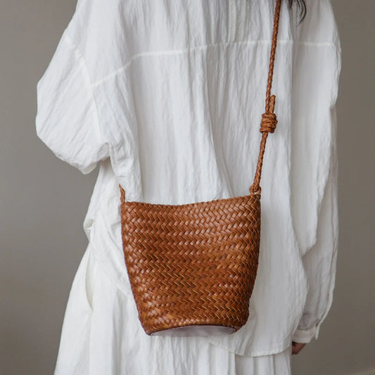 Brown woven leather bucket bag styled crossbody with a white outfit
