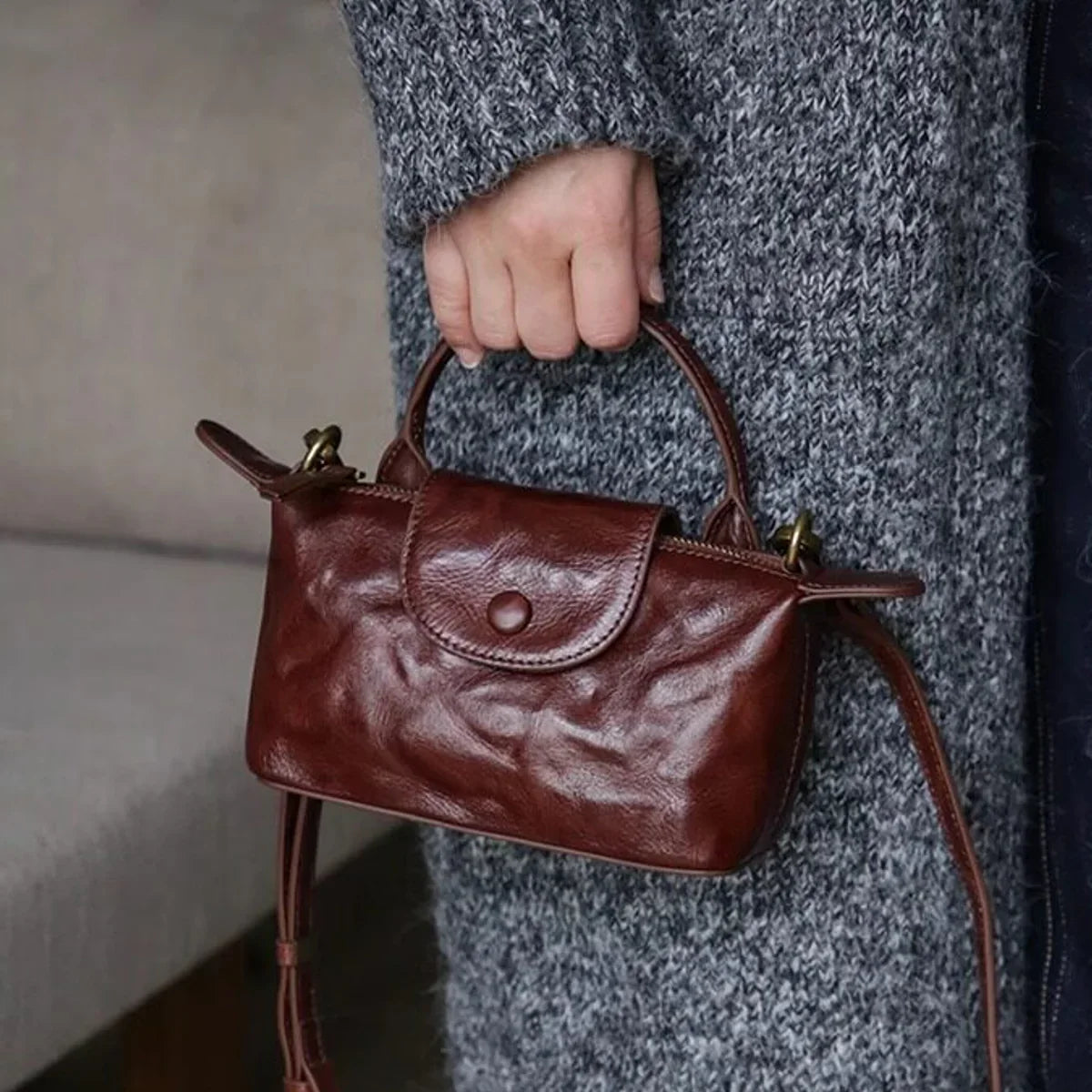 Coffee brown vegetable-tanned leather mini crossbody bag carried by the top handle