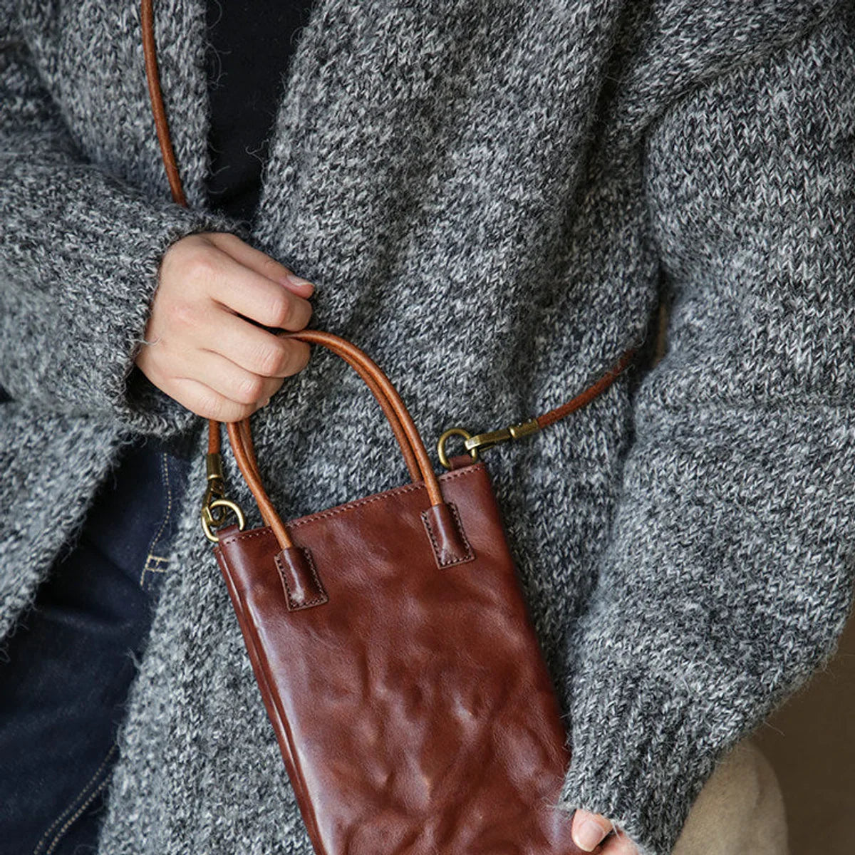 Coffee brown leather mini tote bag carried by its top handles