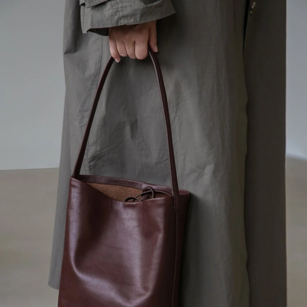 Women's ebony coffee drawstring bucket bag carried by its shoulder strap