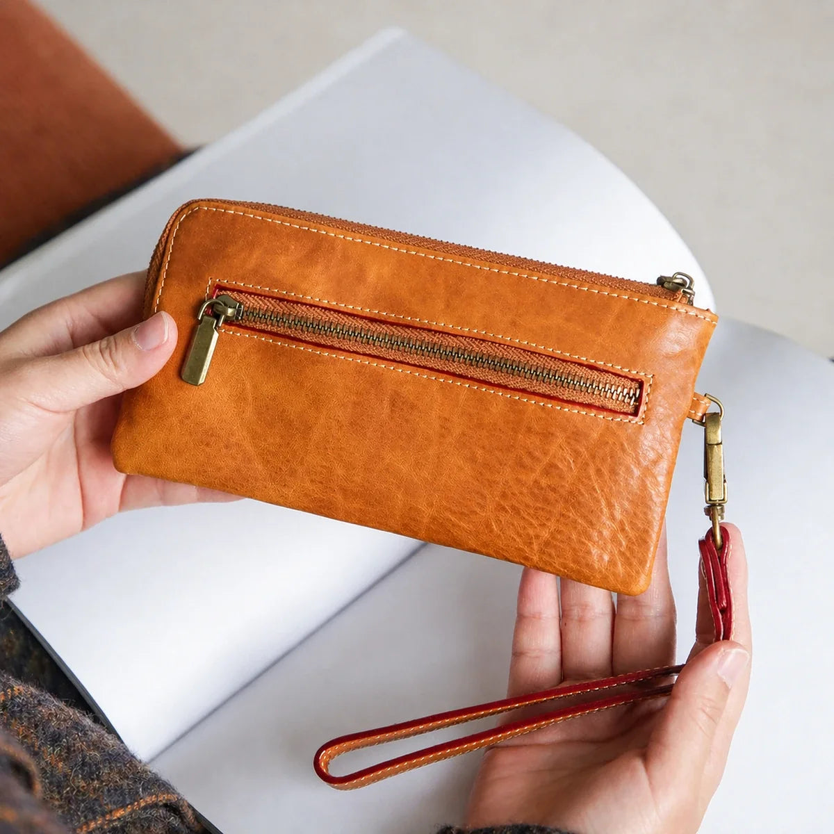 Honey brown cowhide wallet with exterior zip pocket and wrist strap